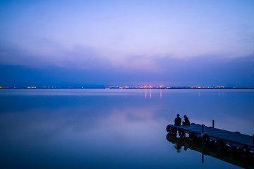 Sunset in the valencia lagoon. Two young people are witnessing the sunset