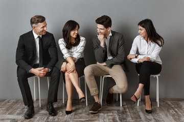 interracial business people in formal wear having conversation while waiting for job interview