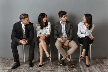 interracial business people in formal wear having conversation together while waiting for job interview
