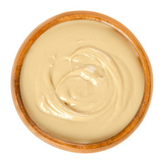 Cashew butter in wooden bowl. Food spread made from roasted cashews. Light brown, smooth food...