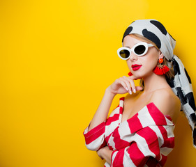 Portrait of beautiful style woman in sunglasses and striped clothes on yellow background