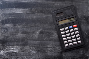 Black digital office calculator with solar panel on school board. Texture. Top view