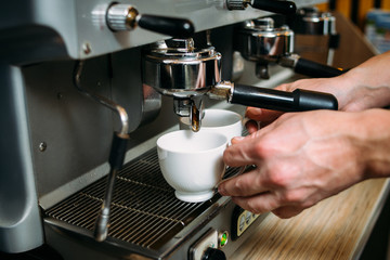 coffee brewing process. professional barista holding two cups for pouring of hot drinks