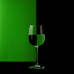Glass wine glass on a black and green background. Mirror image. Different background colors