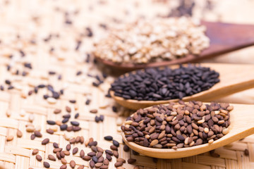 white sesame in wooden spoon on sesame background.