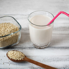 Sesame seed milk in a glass. White sesame seeds on a table. Raw food diet.