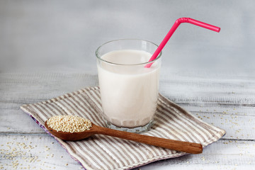 Sesame seed milk in a glass. White sesame seeds on a table. Raw food diet.