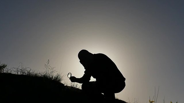 man in gas mask research plants with loupe on ground silhouette