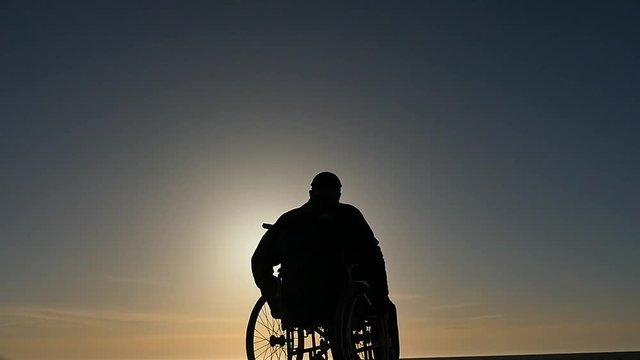 man in wheelchair silhouette motion at sky background
