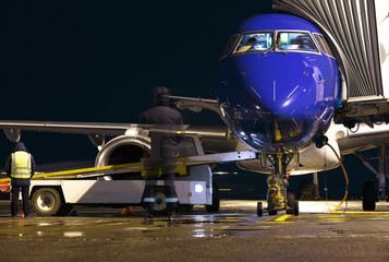 business jet the night in the airport services, security and maintenance engineer in the background of a ramp for Luggage