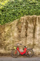 Fototapeta na wymiar Red electric bicycle in front of stone wall