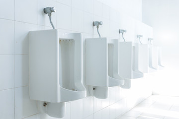 public toilet urinals lined up, no privacy.