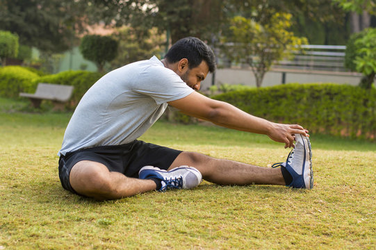 Young guy doing stretching exercise in a park