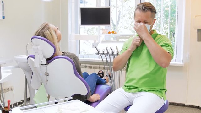 4k footage of smiling male dentist putting on surgical mask and protective latex gloves