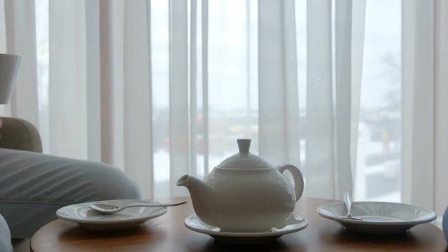 family tea time. beautiful simple teapot and cups on the table. couple drinking hot beverage at home.