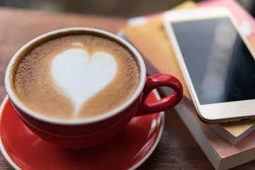 Red cup of coffee with latte art heart shape,soft focus design for valentine background