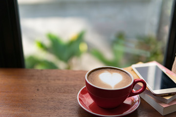 Red cup of coffee with latte art heart shape,soft focus design for valentine background