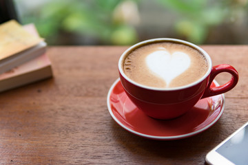 Red cup of coffee with latte art heart shape,soft focus design for valentine background
