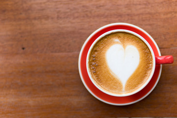Red cup of coffee with latte art heart shape,soft focus design for valentine background