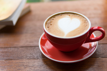 Red cup of coffee with latte art heart shape,soft focus design for valentine background