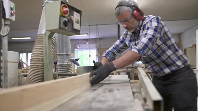 Wood worker cutting piece of wood with machine
