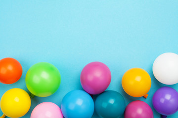 Colorful balloons on blue table top view. Festive birthday background. Flat lay style.