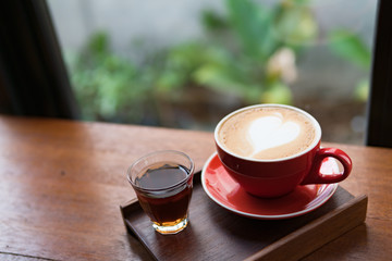 Red cup of coffee with latte art heart shape,soft focus design for valentine background