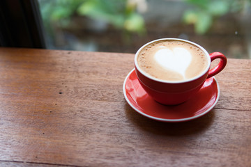 Red cup of coffee with latte art heart shape,soft focus design for valentine background