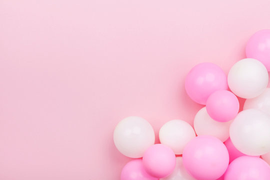 Pastel pink table with colorful balloons for birthday top view. Flat lay style.