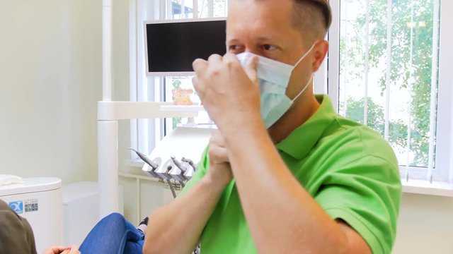 4k video of male dentist putting on surgical medical mask before treting female patient