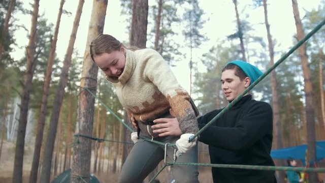 Young happy couple on a rope climbing in the spring forest