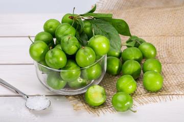 Close Up Of Green Plums Or Greengage in a glass bowl and sprinkle of salt Isolated On White wooden Background, Popular Spring Fruits With A Very Sharp Sour Taste Originated In Iran