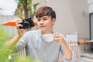 Young man photographer taking picture sitting at table in coffee shop