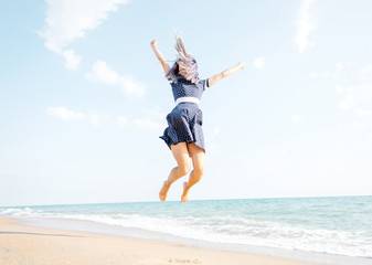 Fototapeta na wymiar Happy woman jumping on sand beach.