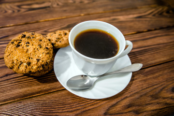 A cup of hot coffee stands on a wooden table 