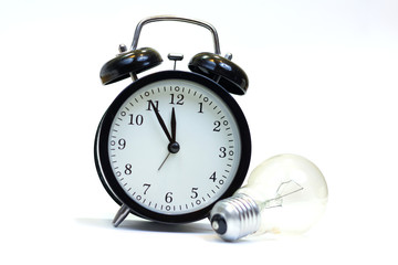 Bulb and vintage clock isolated on a wooden table