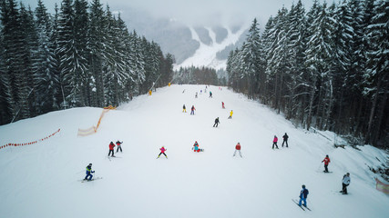 Skiers and snowboarders go down the slope in a ski resort Bukovel, Ukraine