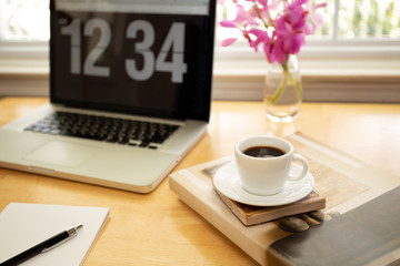 Cup of coffee on wooden desk with laptop computer