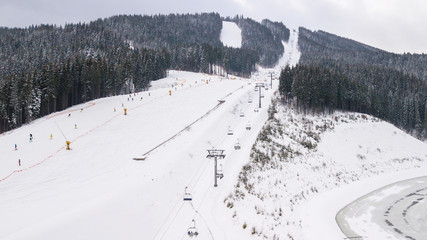 Skiers and snowboarders go down the slope in a ski resort Bukovel, Ukraine