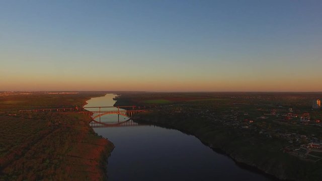 Panorama of the wooded coastline of a large river next to a large city during sunset. Dnieper River, Zaporozhye, Ukraine. Aerial view.