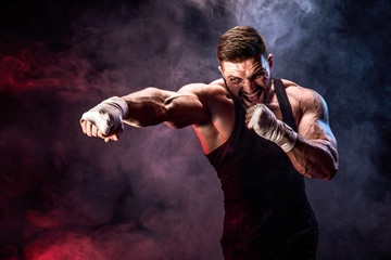 Sport concept. Sportsman muay thai boxer fighting on black background with smoke. Copy Space.