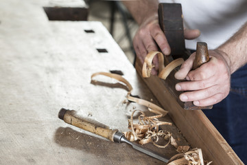 carpenter working with plane on wooden background