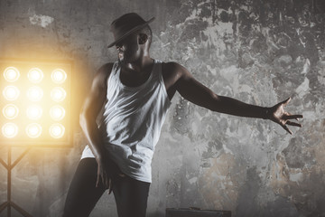 a young black man dancing  in front of a rustic wall background