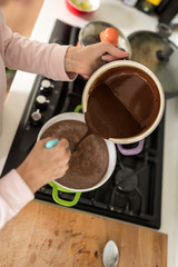 Overhead view of a cook emptying chocolate sauce from a pot