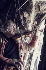 Old man playing music on a classical wooden violin