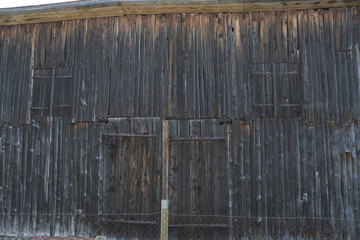 View of a weathered wooden shed with a fence in front