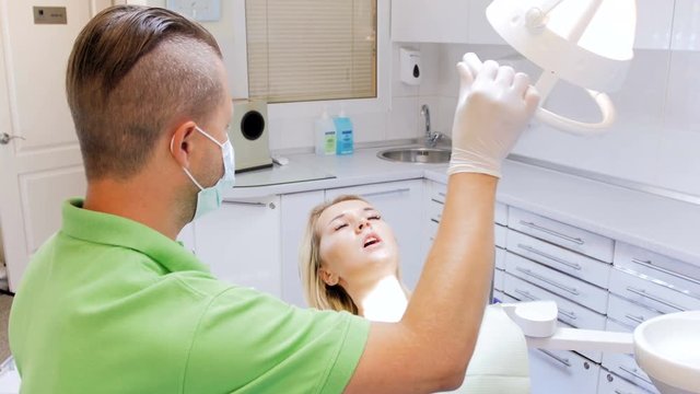 4k footage of dentist adjusting lamp while inspecting patient's teeth