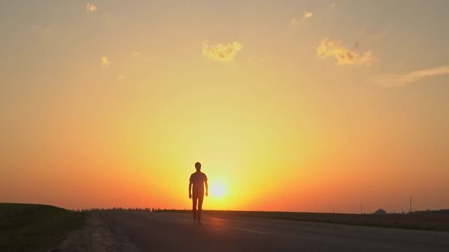 The man is walking in the sunset.