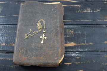 Christian cross with the old holy Bible on the table