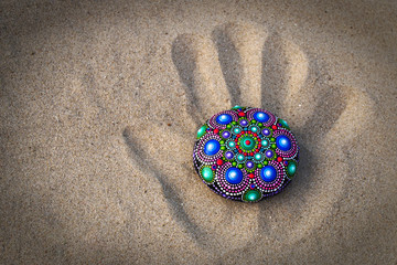 hand painted mandala rock on sand